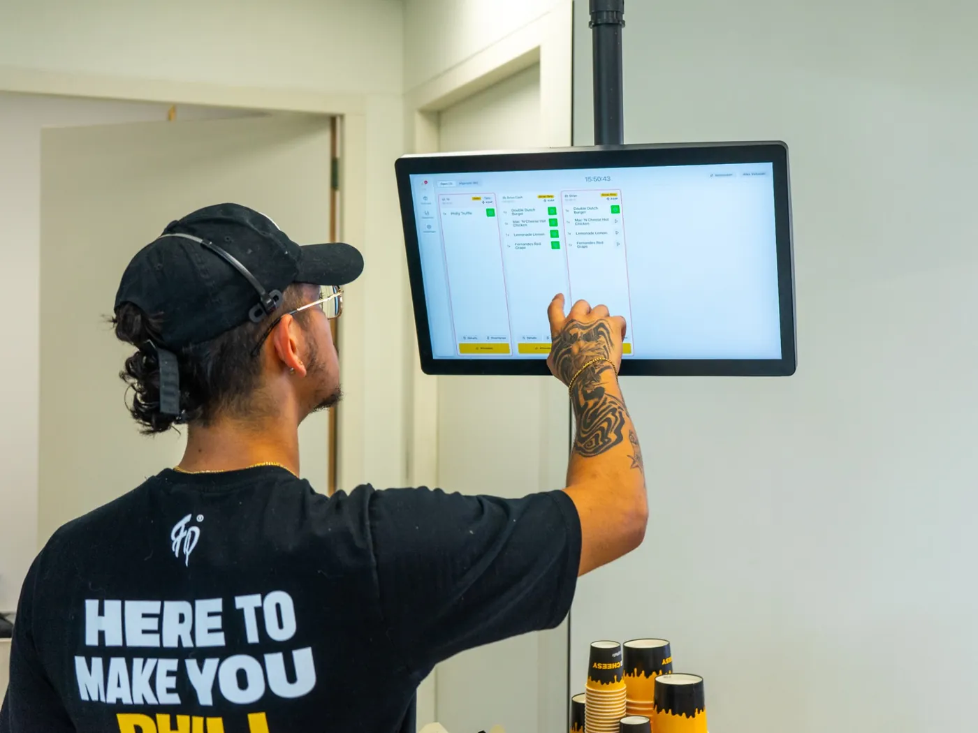 Medewerker van Fat Phill's vinkt een Drive-Thru-order af op het Onesix Keuken Scherm