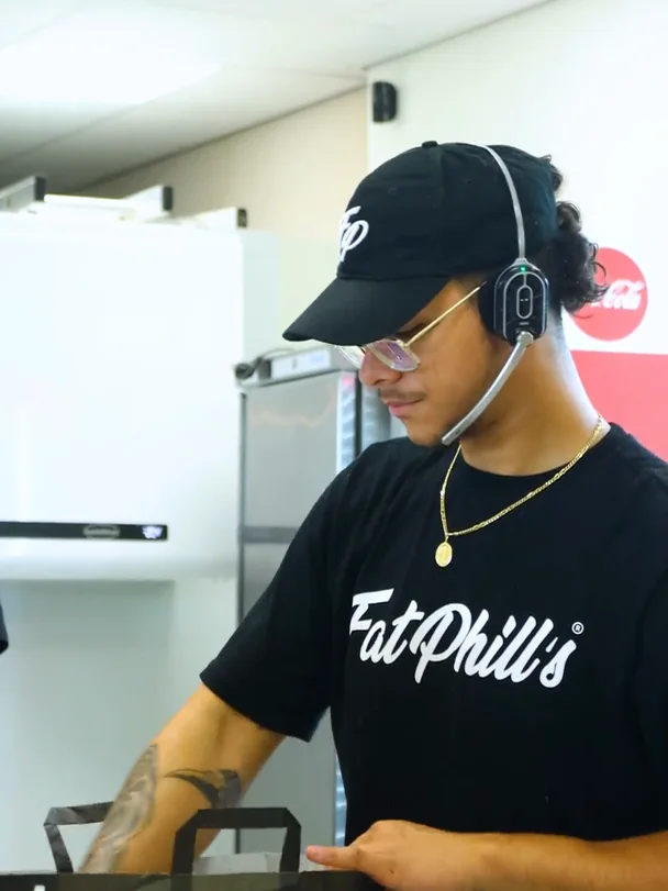 Medewerker van Fat Phill's met headset pakt een Drive-Thru-bestelling in