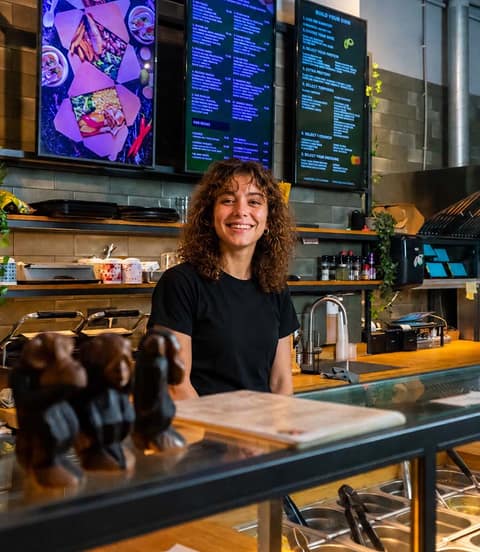 Medewerker van Grlla Kitchen achter de toonbank met Onesix menuschermen