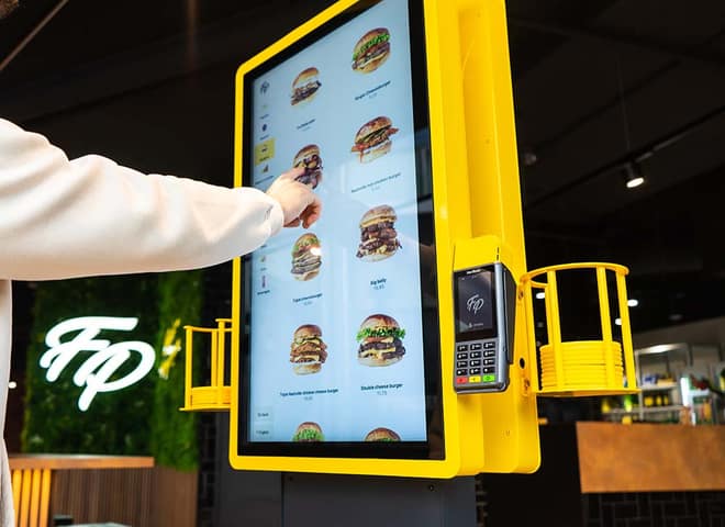 Gast bestelt aan de gele Onesix Kiosk bij Fat Phill's