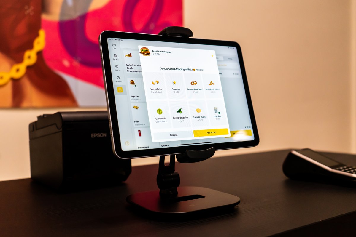 Onesix Kassa op een tablet met een upsell-scherm, naast een bonprinter en een betaalterminal
